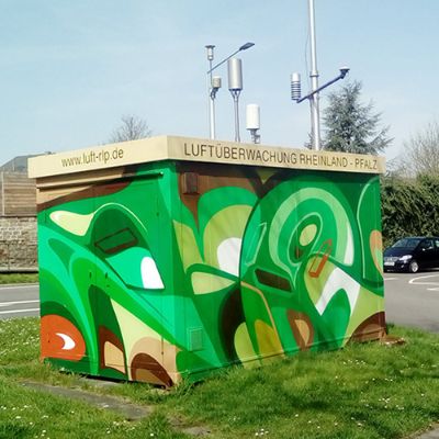 Ein mit grünen Graffitis bemaltes Gehäuse an einer Straße